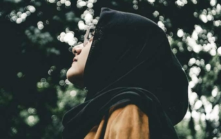 Young Muslim woman looking upwards in a forest.
