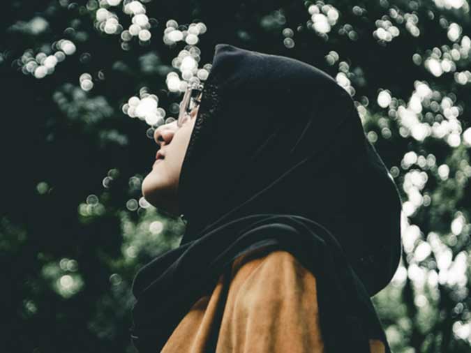 Young Muslim woman looking upwards in a forest.