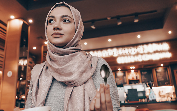Muslim woman at Cafe holding a spoon.