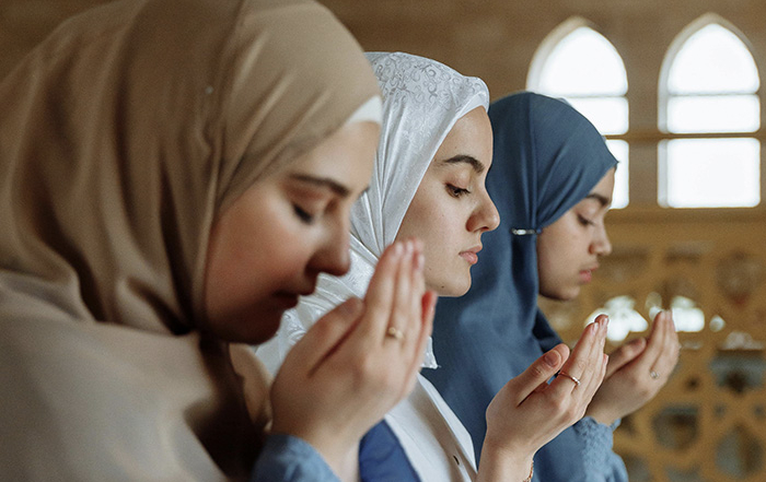 3 Muslim women in hijab praying together side by side
